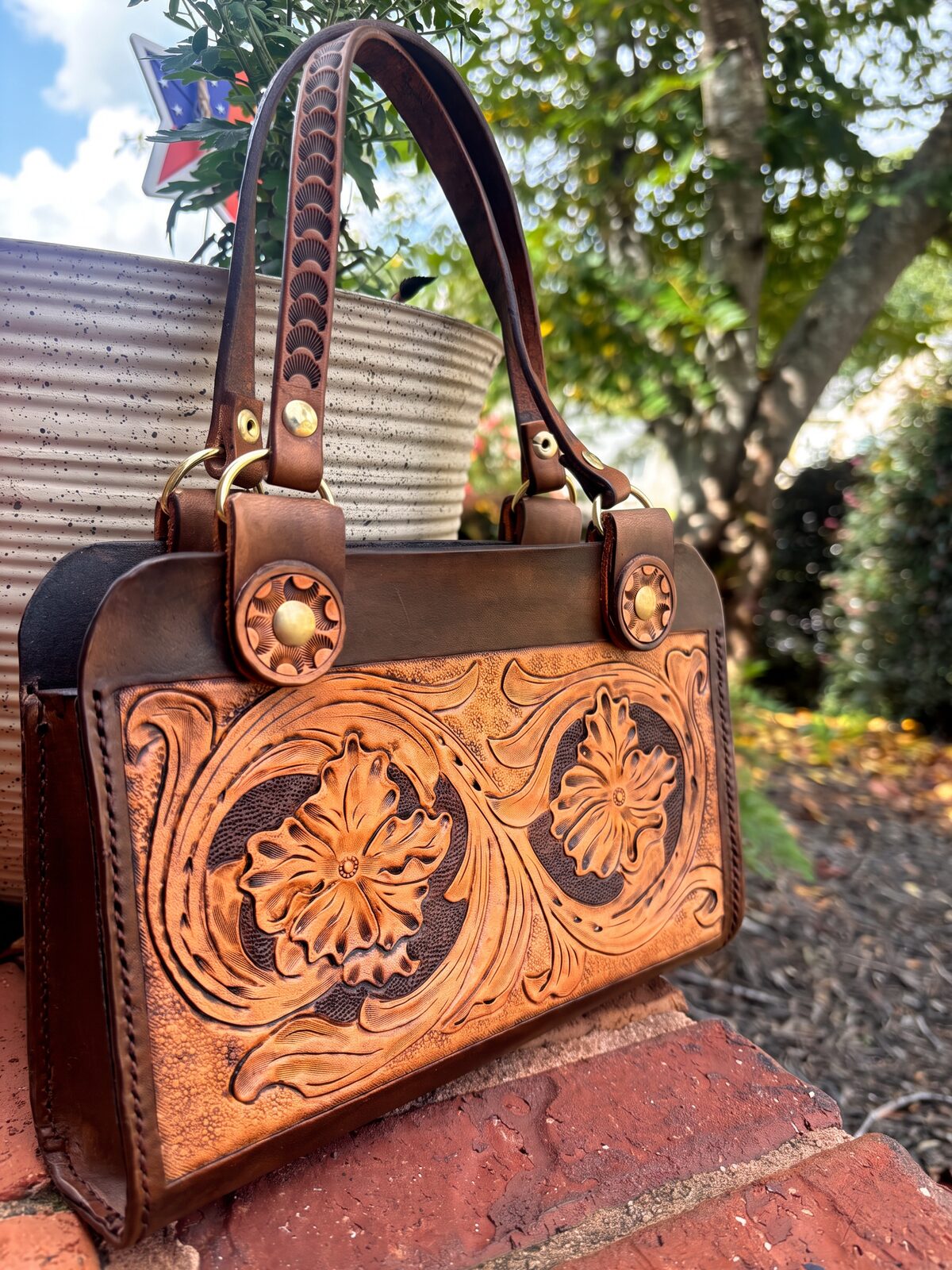 Hand-tooled western tote in caramel leather with a dark brown frame and brass hardware